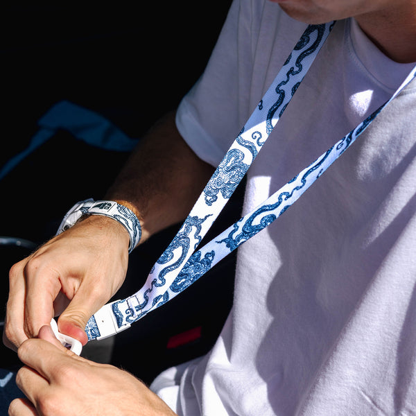 A person in a white shirt wears a Freestyle Lanyard & Key Chain - Octopus by Freestyle while interacting with an object.