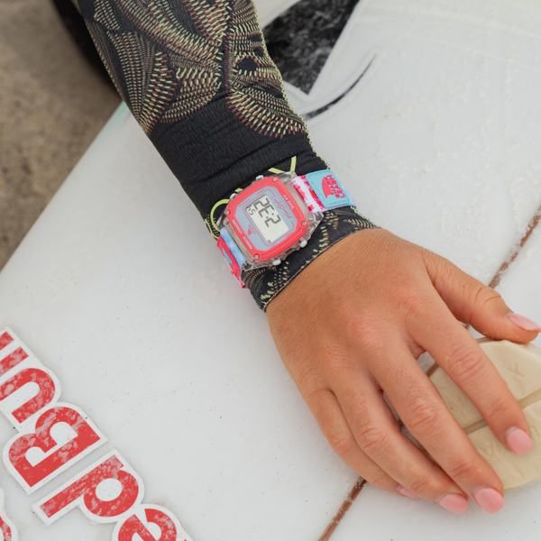 A hand in a wetsuit with a Freestyle CAROLINE MARKS SIGNATURE SHARK CLASSIC LEASH SURFIN USA is placed on a surfboard.